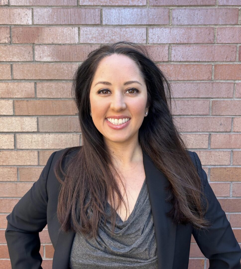 A woman standing in front of a brick wall.