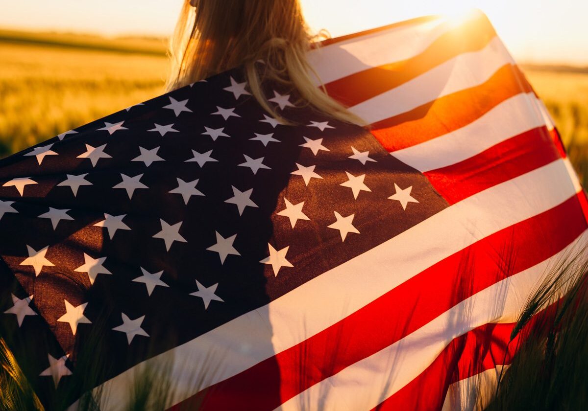A woman holding an american flag in the sun.