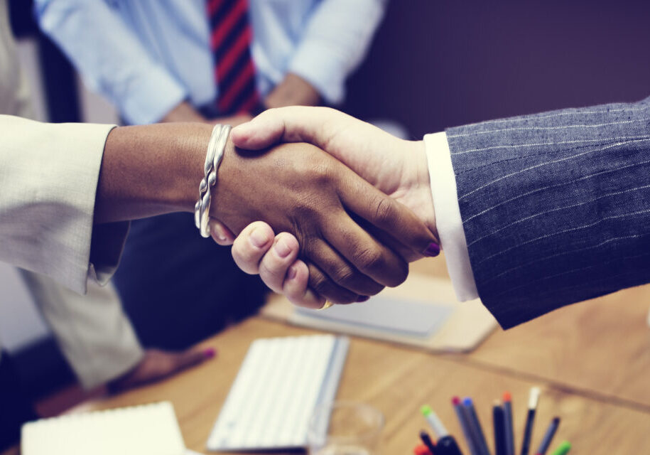 Two people shaking hands over a desk.